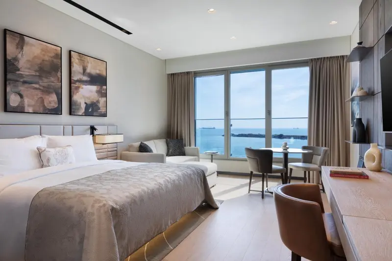 Chambre lumineuse avec un grand lit et une vue sur la mer.