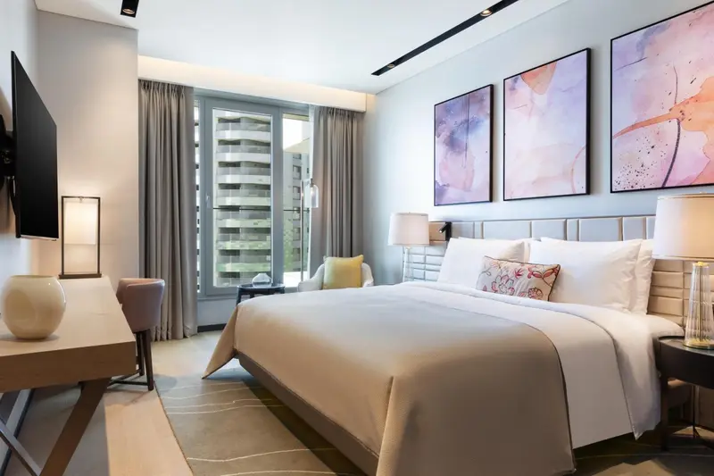 Une chambre lumineuse avec un grand lit et un accès à un balcon.