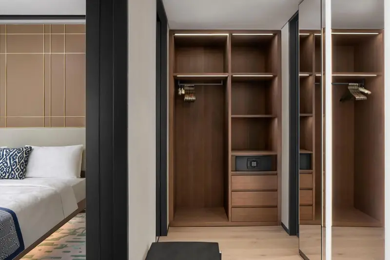 Intérieur d'une chambre avec un placard ouvert et un lit partiellement visible.