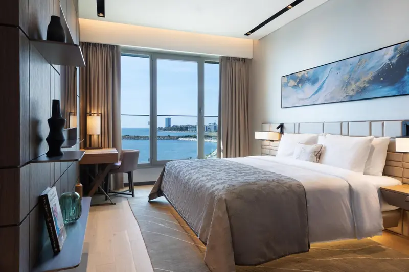 Chambre lumineuse avec un grand lit et vue sur la mer.
