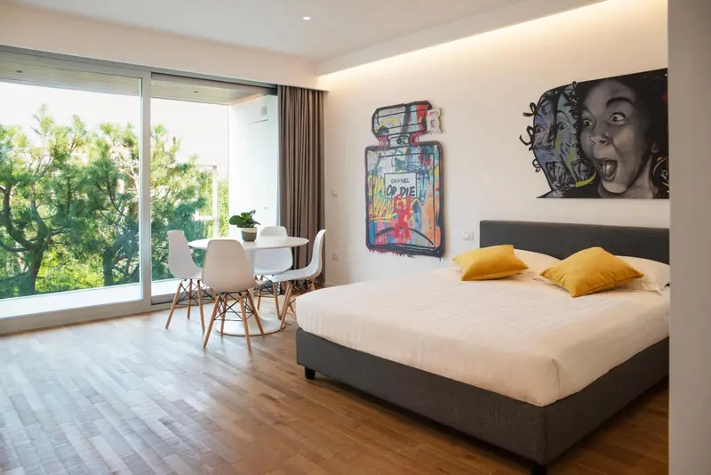 Une chambre lumineuse avec un grand lit et un coin repas près d'une fenêtre.