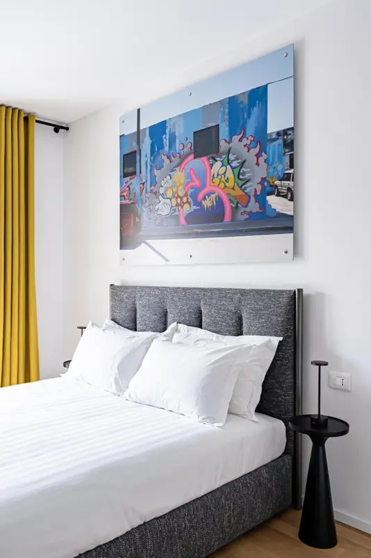 Une chambre lumineuse avec un grand lit et une décoration murale colorée.