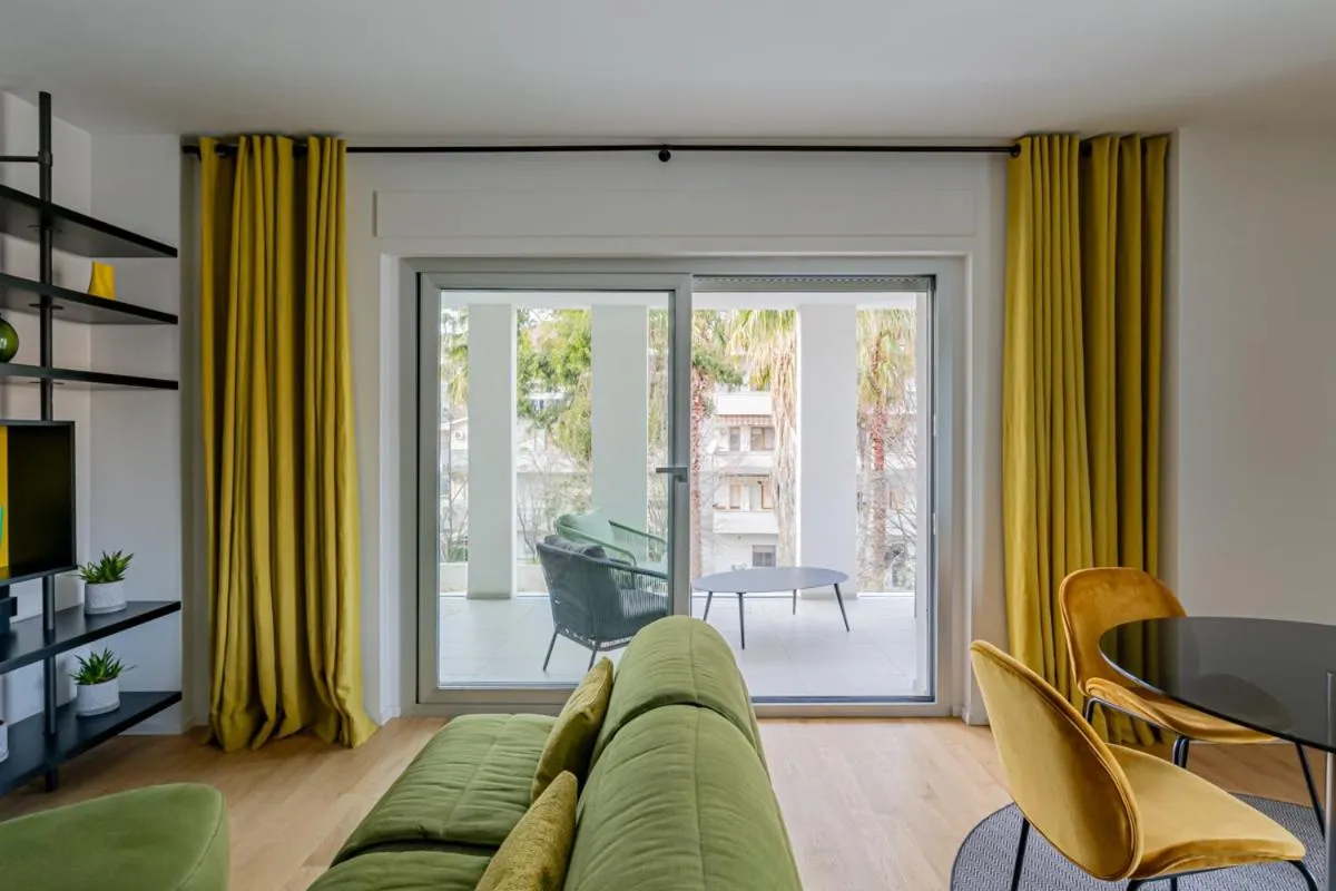 Espace de vie lumineux avec canapé vert et accès à une terrasse.
