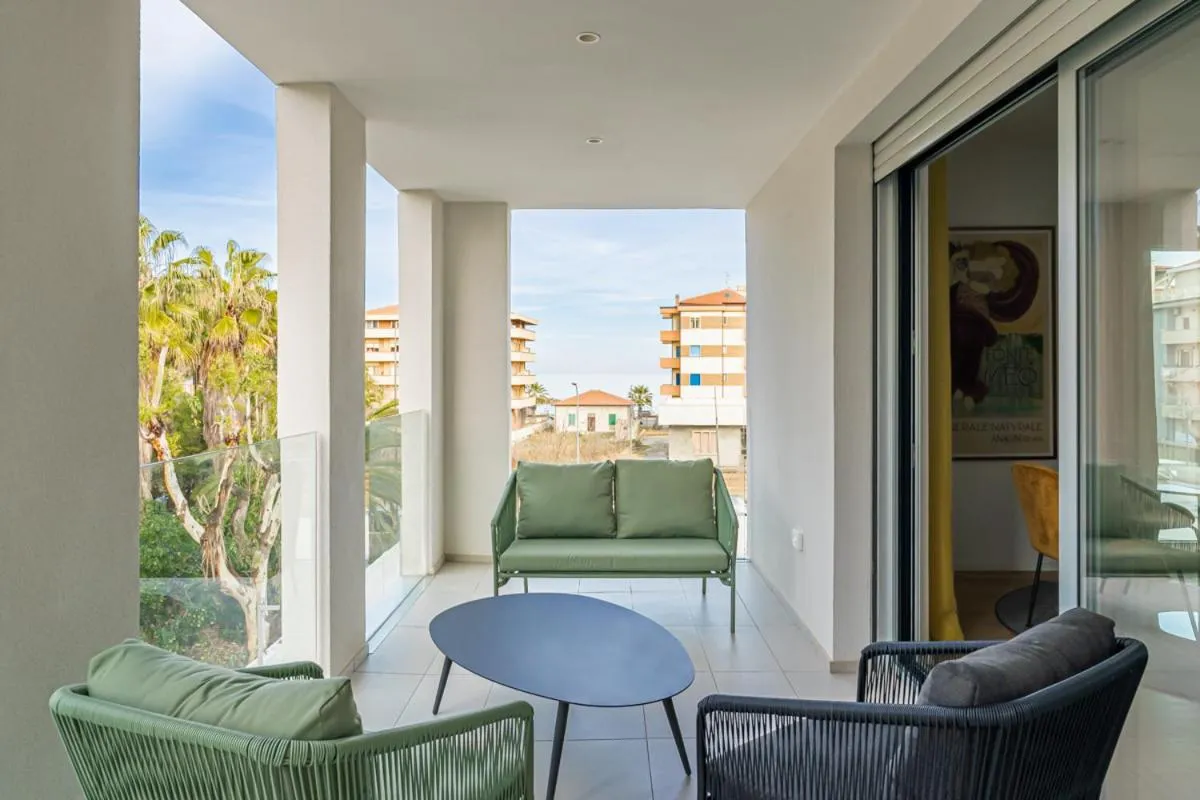 Terrasse aménagée avec canapés et table basse donnant sur une vue urbaine et la mer.