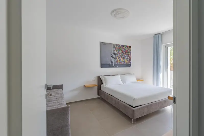 Une chambre lumineuse avec un grand lit et une décoration murale colorée.