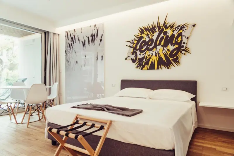 Une chambre lumineuse avec un grand lit et une décoration murale colorée.