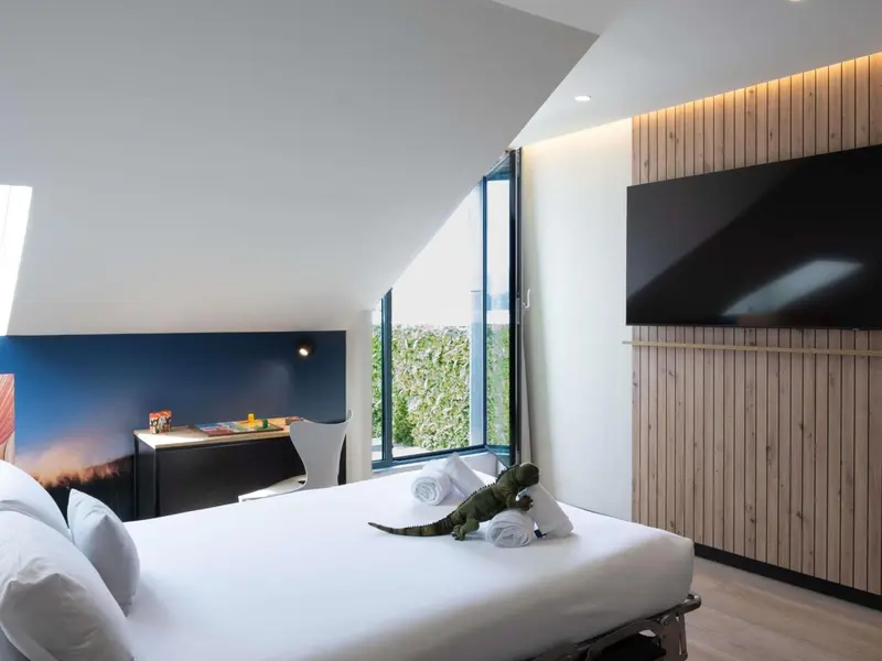 Une chambre lumineuse avec un grand lit et une fenêtre donnant sur un jardin.