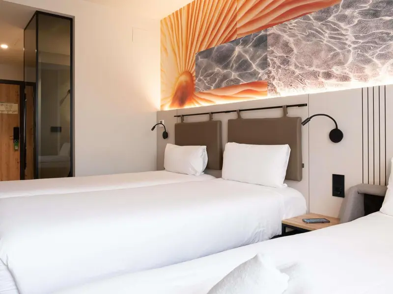 Une chambre lumineuse avec deux lits simples et une décoration murale abstraite.