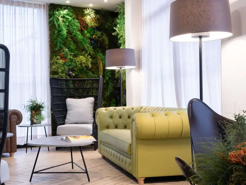 Un salon lumineux avec un mur végétal et des fauteuils confortables.