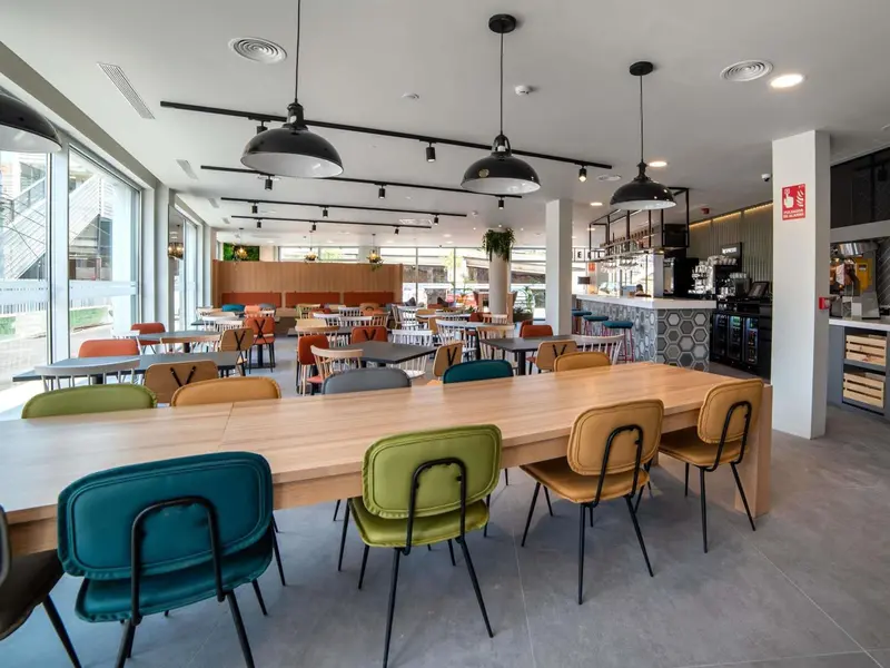 Une salle lumineuse avec de longues tables et des chaises colorées.