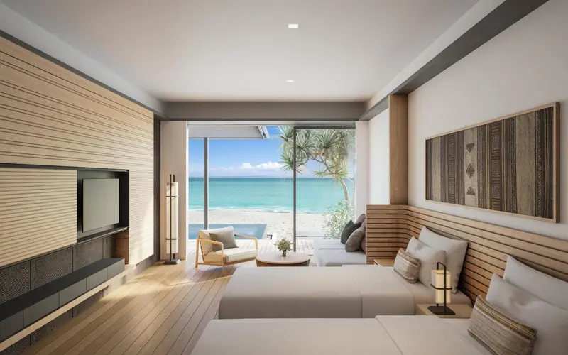 Une chambre lumineuse donne sur une plage de sable blanc et une mer turquoise.