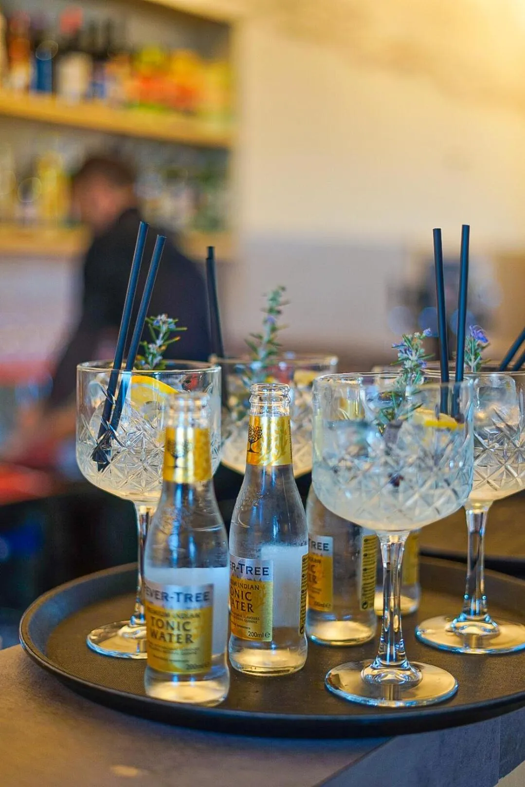 Des verres et des bouteilles de boissons fraîches sont disposés sur une table sombre.