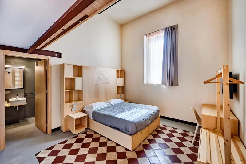 Une chambre lumineuse avec un lit simple et un bureau en bois.