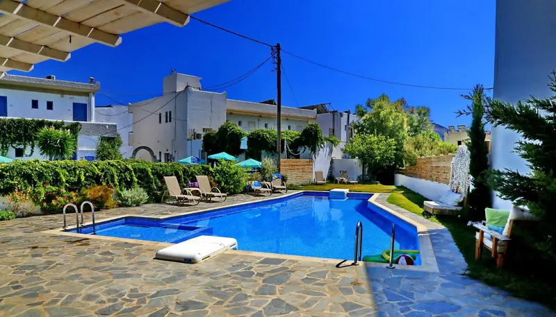 Une piscine rectangulaire entourée d'une terrasse pavée et de chaises longues.
