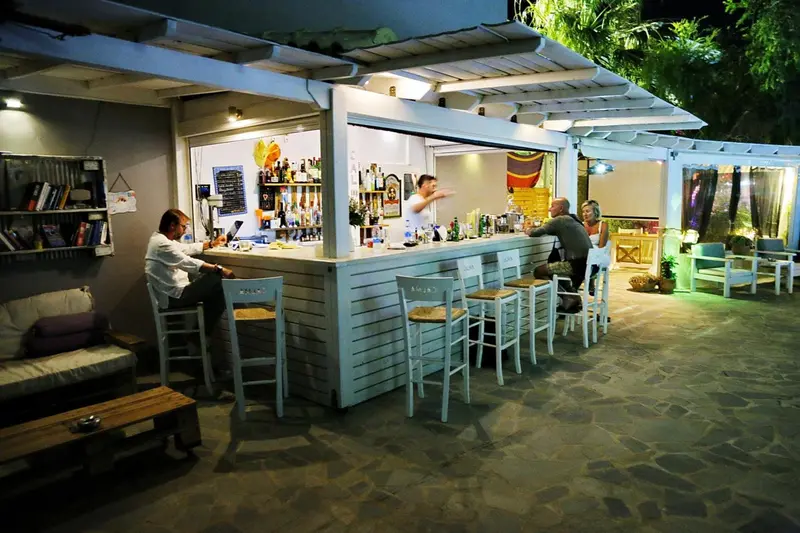 Un bar en plein air avec des clients assis au comptoir et sur des tabourets.