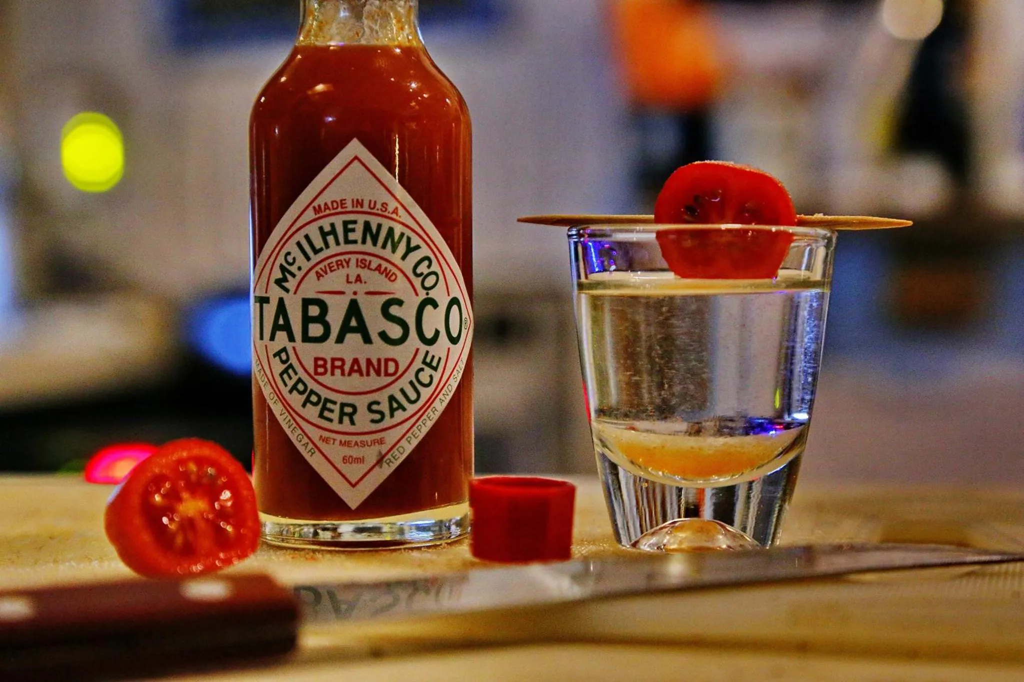 Une bouteille de sauce piquante et un verre décoré d'une tomate.