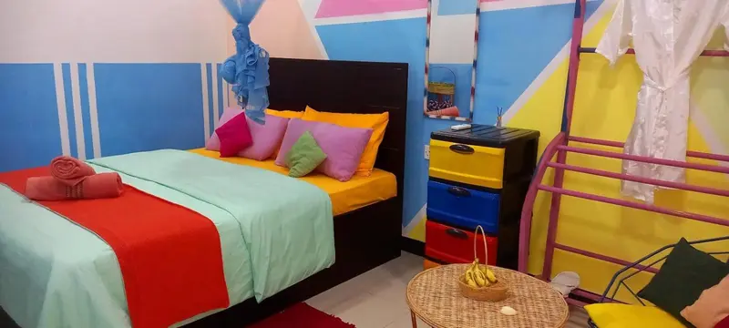 Une chambre colorée avec un lit recouvert d'un couvre-lit orange et turquoise.
