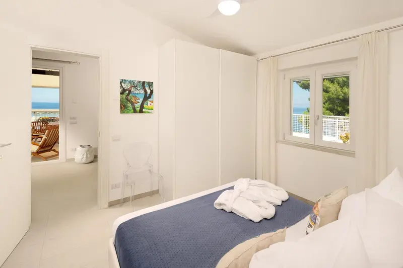 Une chambre lumineuse avec un lit fait et une vue sur la mer.