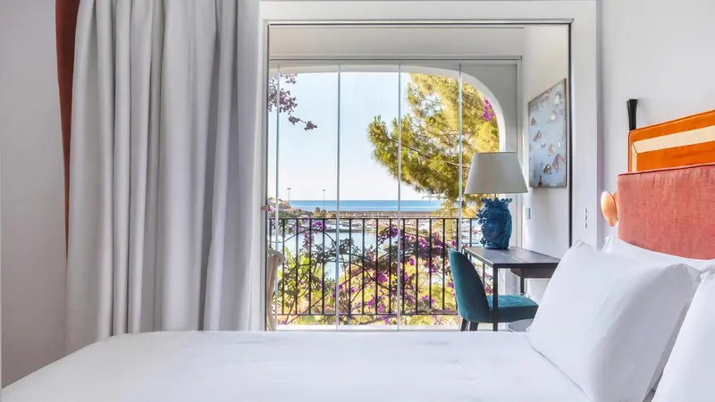 Une chambre lumineuse avec vue sur la mer et la végétation.