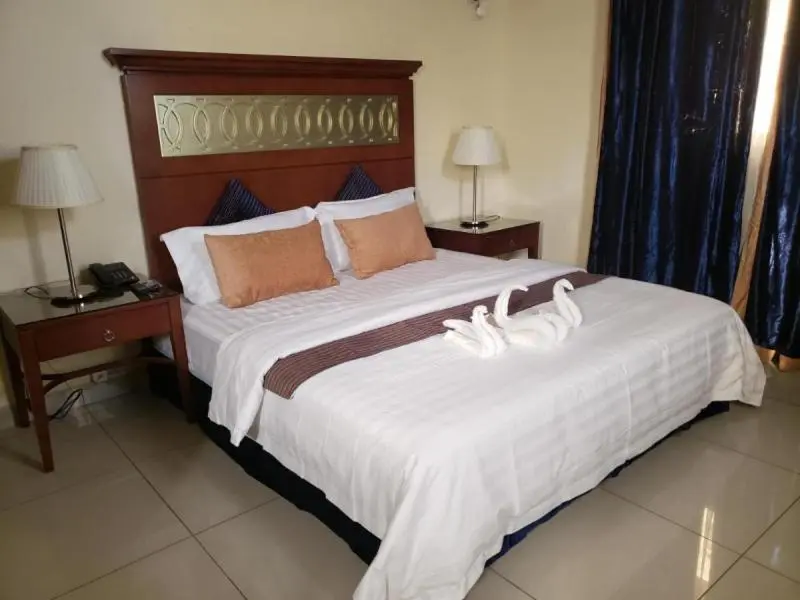 Une chambre d'hotel avec un grand lit recouvert de draps blancs et de coussins.