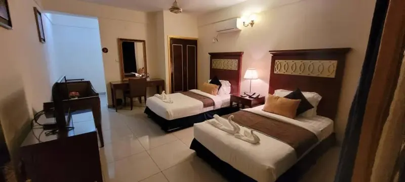 Une chambre avec deux lits simples et un bureau.