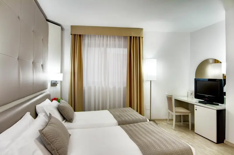 Une chambre lumineuse avec deux lits simples et un bureau.