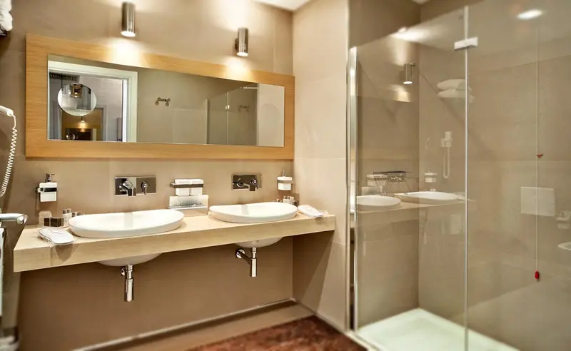 Une salle de bain moderne avec deux vasques et une douche vitrée.
