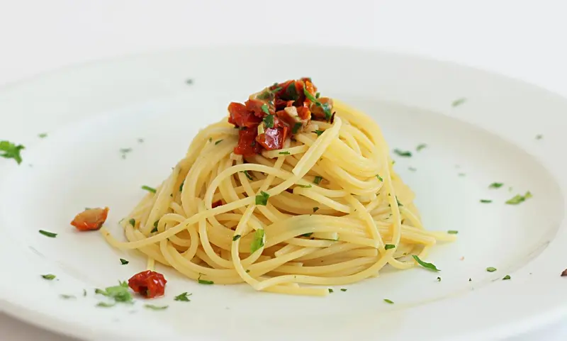 Assiette de spaghetti aux tomates cerises et herbes fraîches.