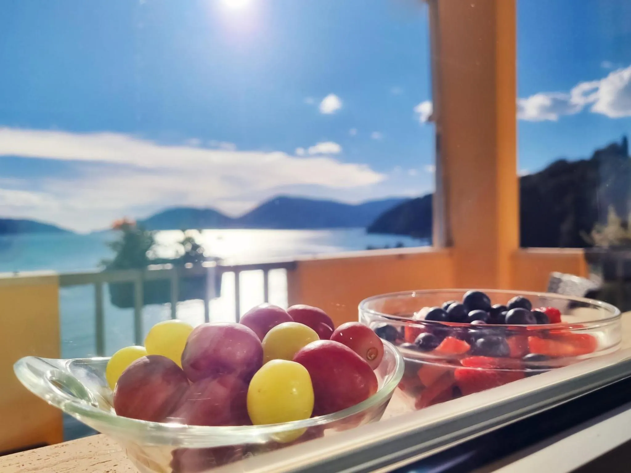 Des fruits frais disposés sur une table en terrasse avec vue sur la mer.