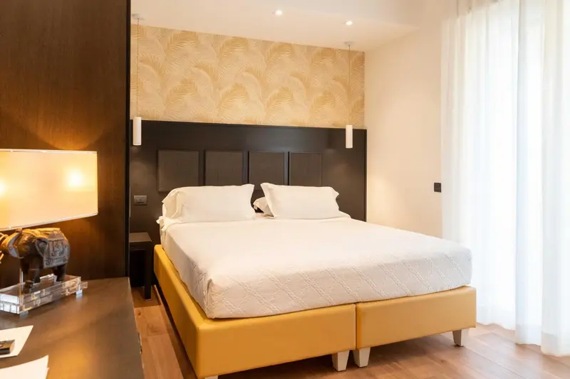 Une chambre lumineuse avec un grand lit recouvert d'une couette blanche.