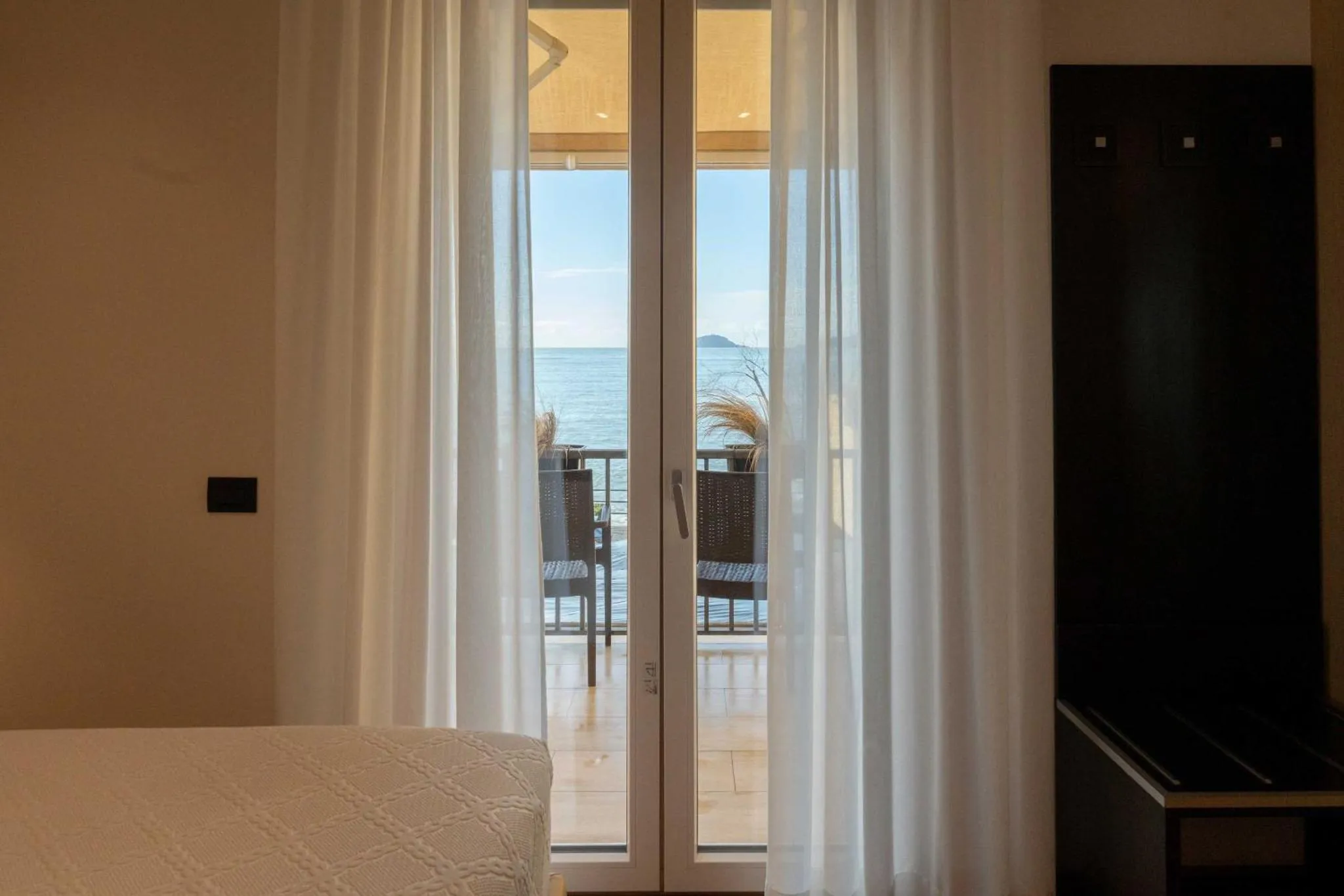 Une chambre lumineuse s'ouvre sur une terrasse avec vue sur la mer.