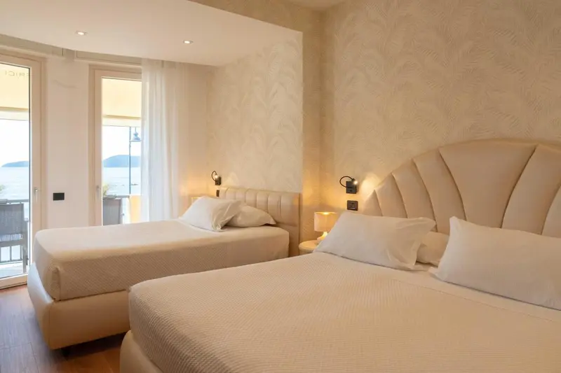 Chambre lumineuse avec deux lits et vue sur la mer.