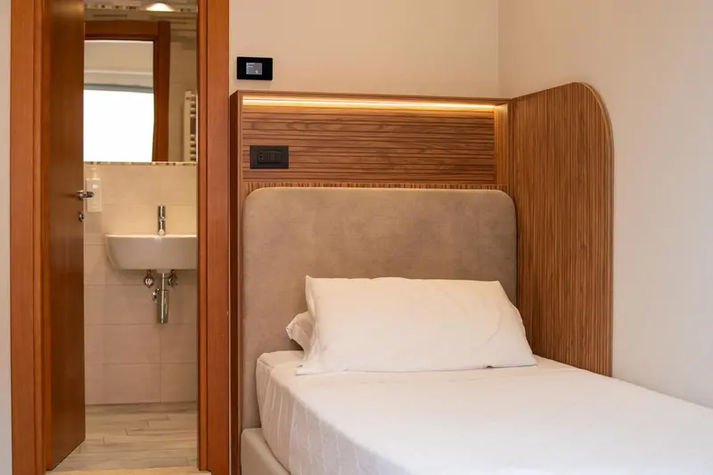 Une chambre lumineuse avec un lit simple et un accès à une salle de bain.