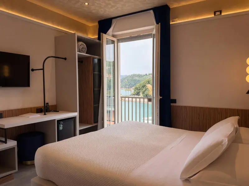 Une chambre lumineuse avec un lit blanc donnant sur une vue mer.