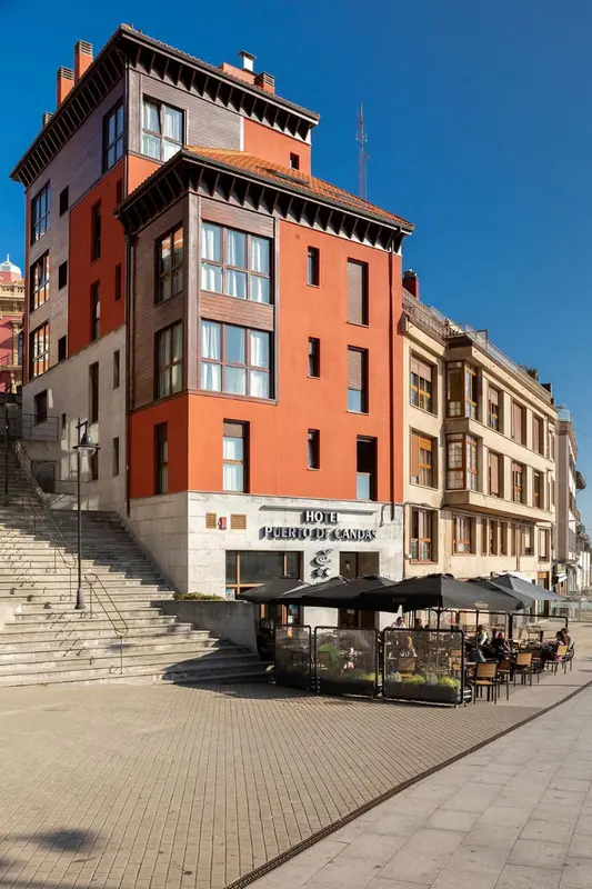 Façade d'un bâtiment rouge et ocre avec des fenêtres et un escalier en pierre.