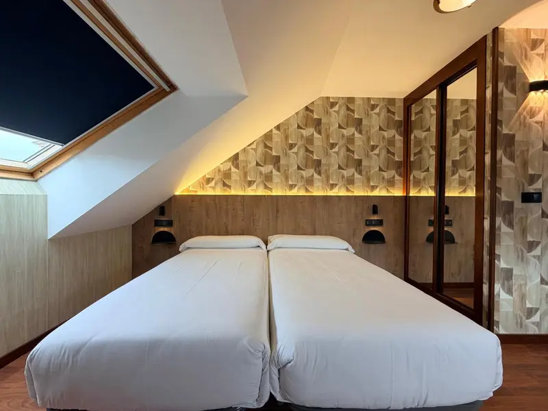 Une chambre avec deux lits simples et un décor mural texturé.