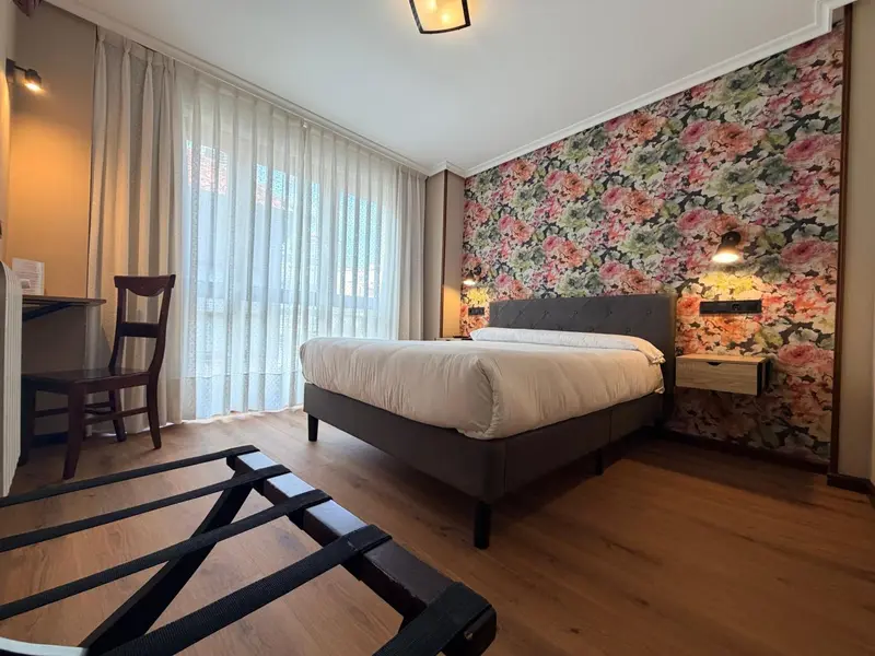 Une chambre lumineuse avec un lit double et un bureau.