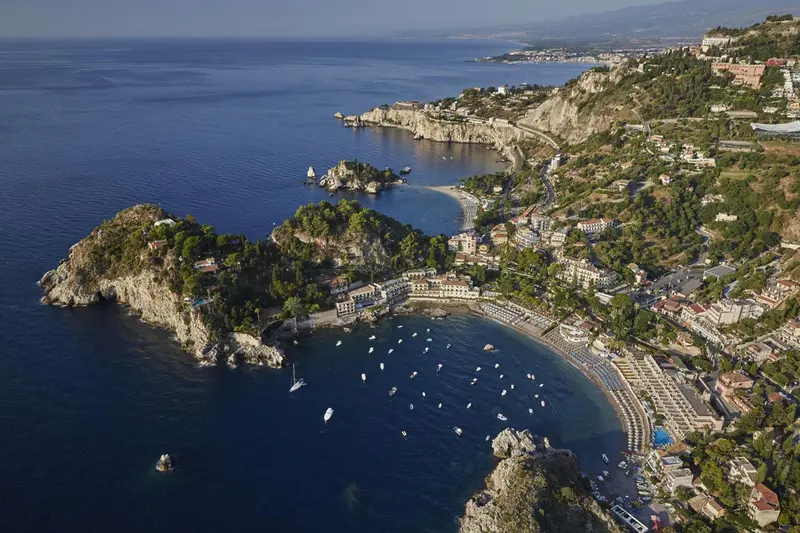 Vue aérienne d'une côte rocheuse avec une plage et des embarcations.