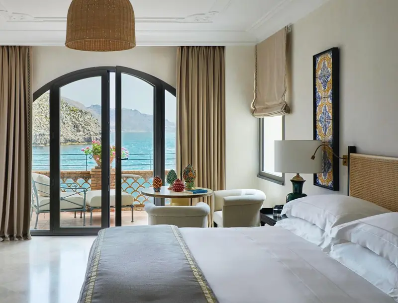 Une chambre lumineuse avec un grand balcon donnant sur la mer.