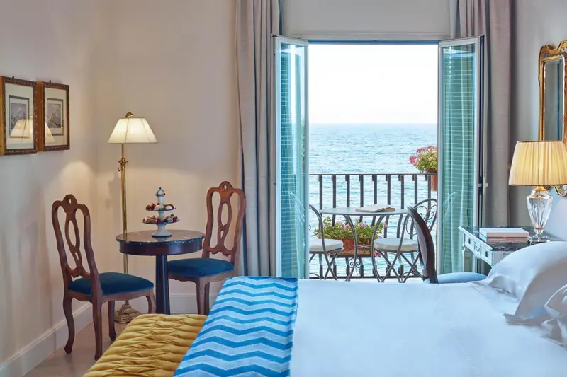 Une chambre lumineuse s'ouvre sur un balcon avec vue sur la mer.