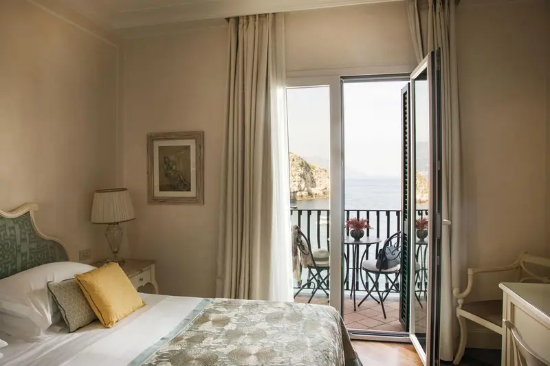 Une chambre lumineuse s'ouvre sur une terrasse avec vue sur la mer.