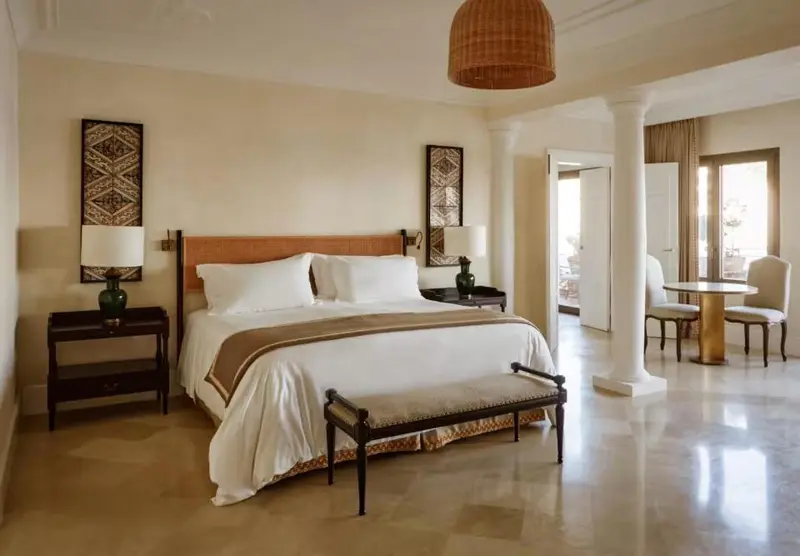 Une chambre lumineuse avec un grand lit et un coin repas.