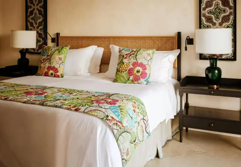 Une chambre lumineuse avec un grand lit décoré de coussins colorés.