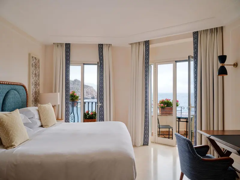 Une chambre lumineuse avec un grand lit donnant sur une vue mer.