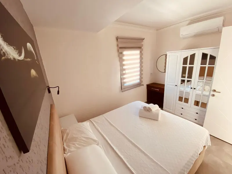 Une chambre lumineuse avec un grand lit et un placard blanc.