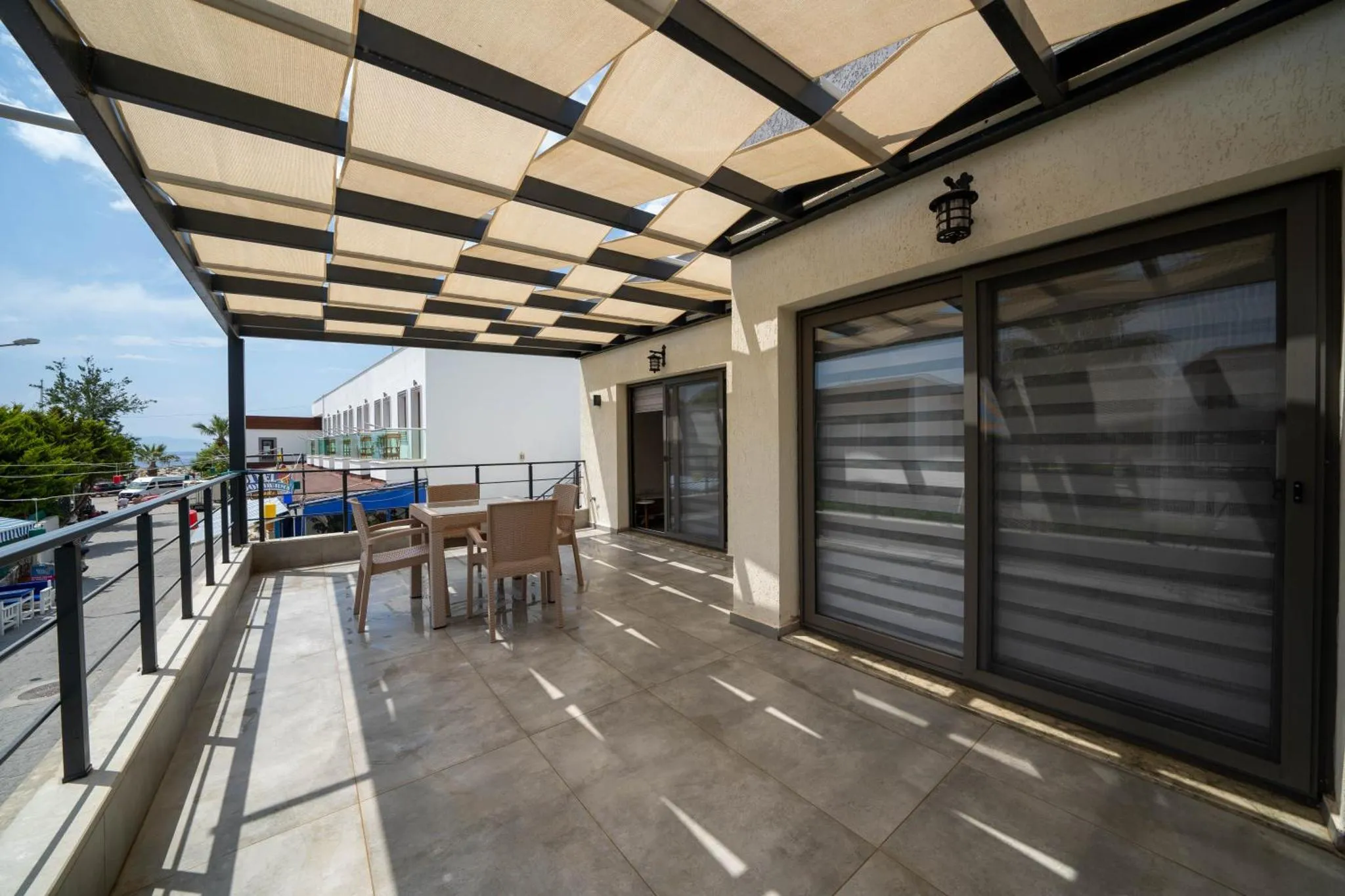 Terrasse ombragée avec mobilier de jardin et vue sur la mer.