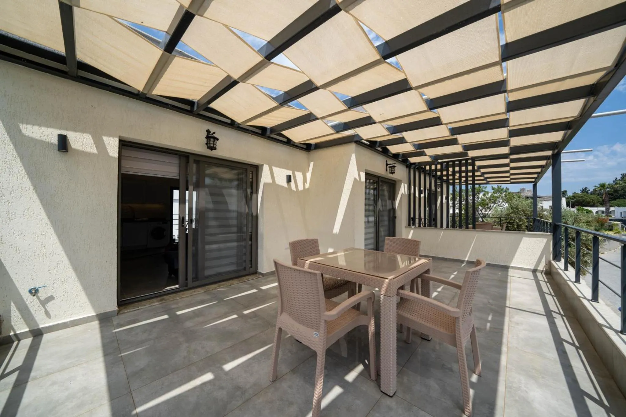 Terrasse ombragée avec table et chaises en osier.