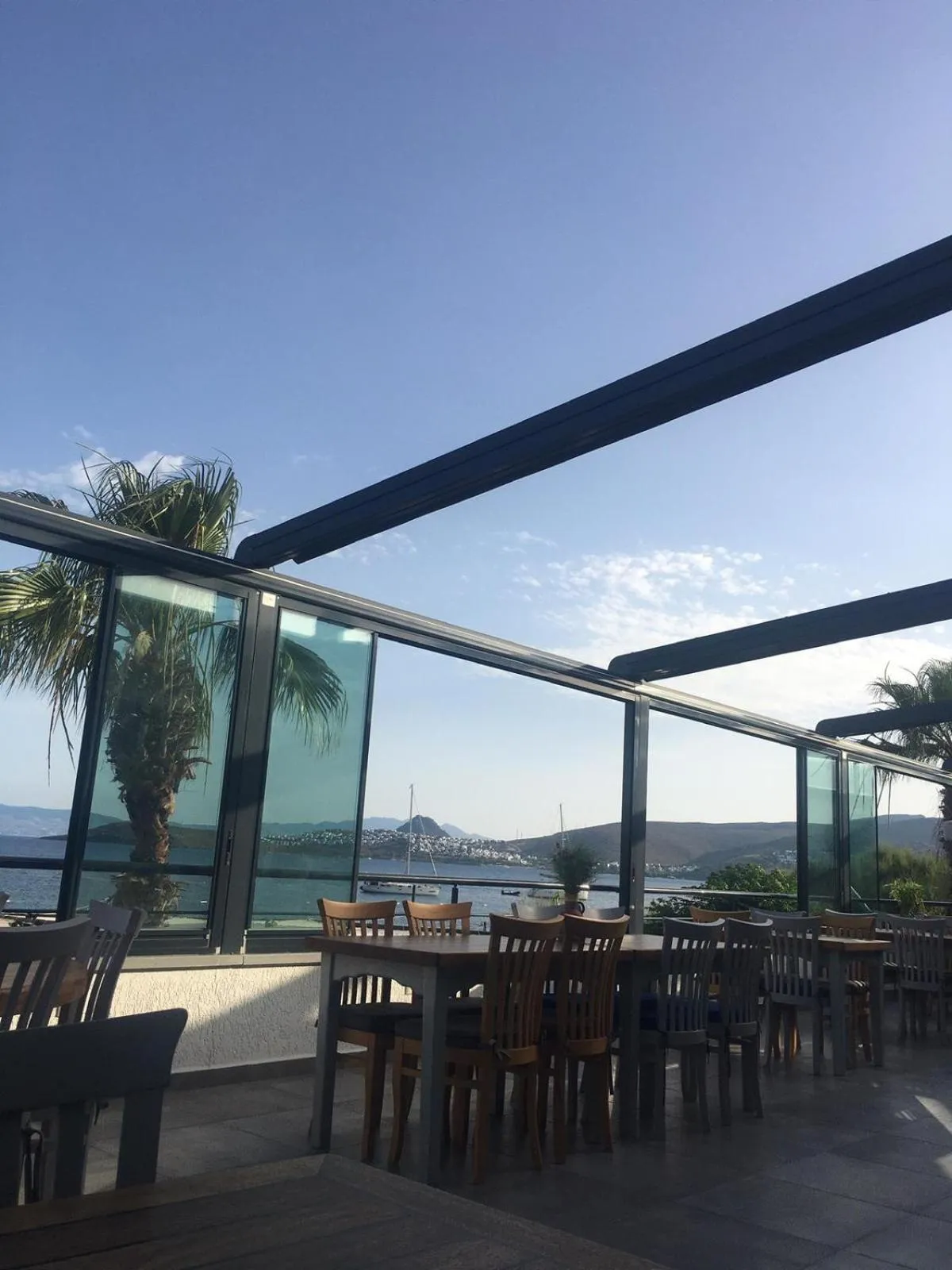 Terrasse ombragée avec tables et chaises donnant sur la mer.