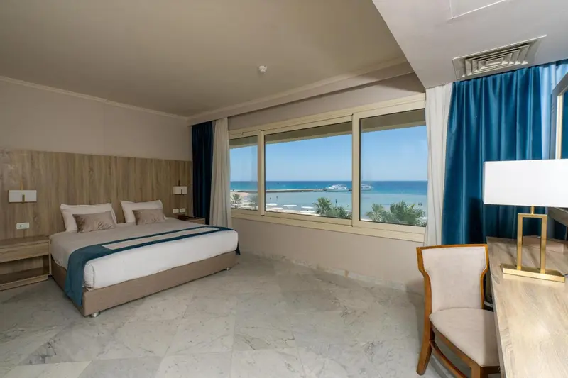 Chambre lumineuse avec un grand lit et vue sur la mer.