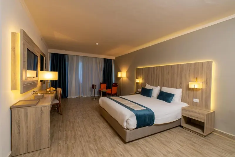 Chambre lumineuse avec un grand lit et un bureau.